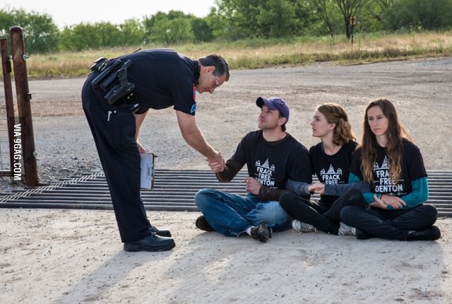 Police officer shakes hand of fracking protester before arresting him