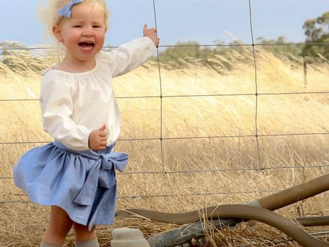 Australian mother unknowingly takes photo of huge venomous snake next to her little girl.