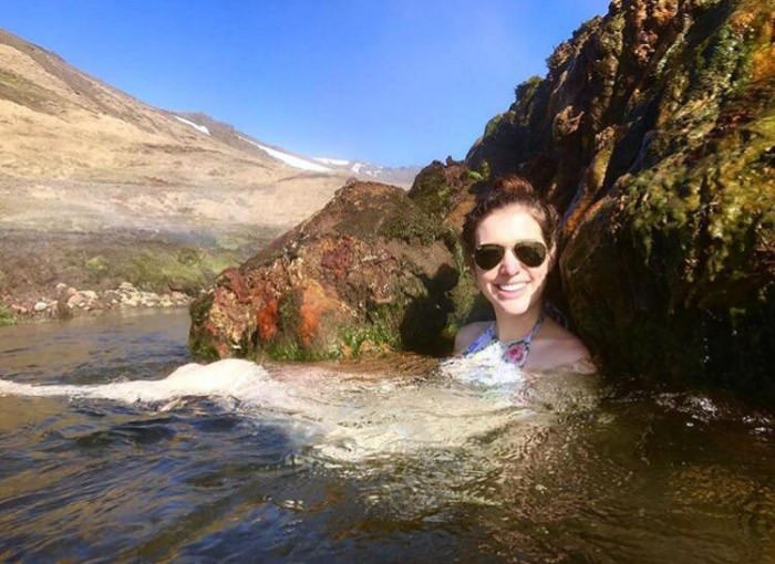 This woman seems as if she&#039;s a giant lounging in the ocean on a large mountain.